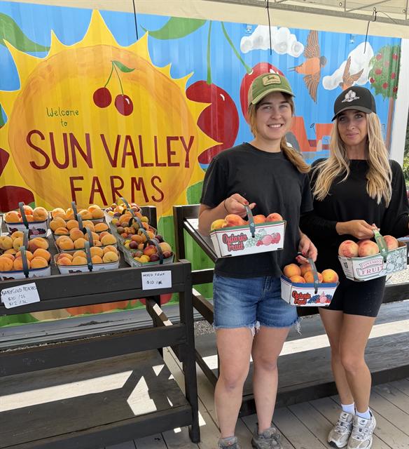 Nicole at Sun Valley Farms holding baskets of peaches